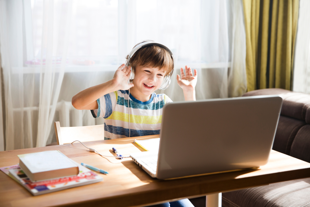 Happy child attending an online Quran class, learning with headphones and laptop in an interactive session.