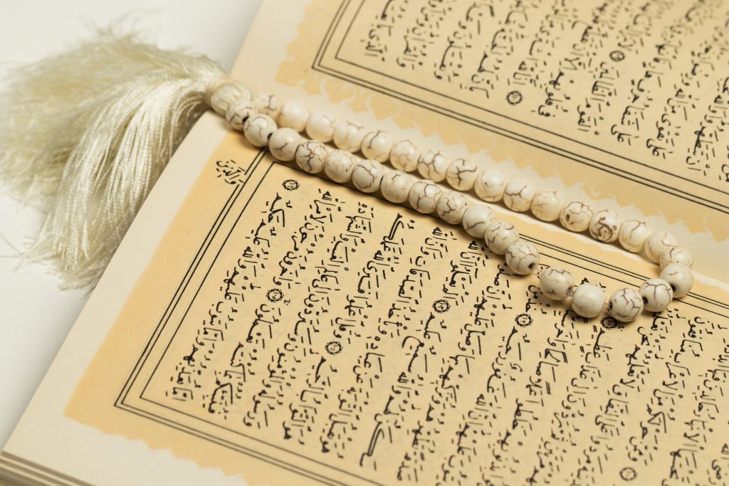 Open Quran with prayer beads symbolizing global students learning the Quran online.