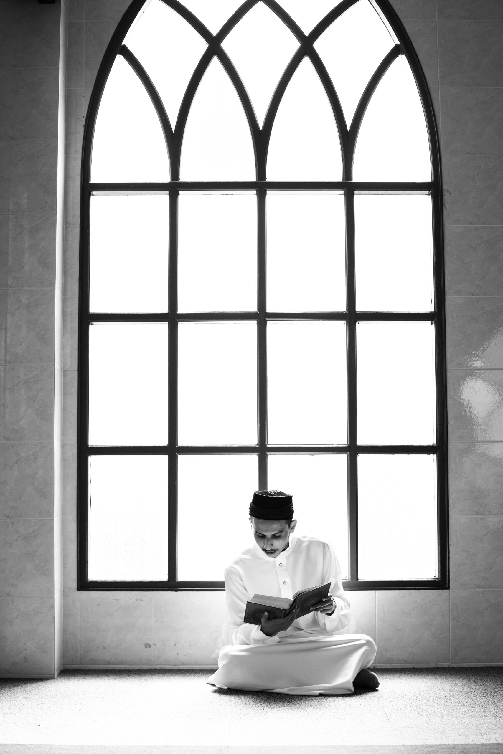 Muslim man studying the Quran near a window during Quran lessons