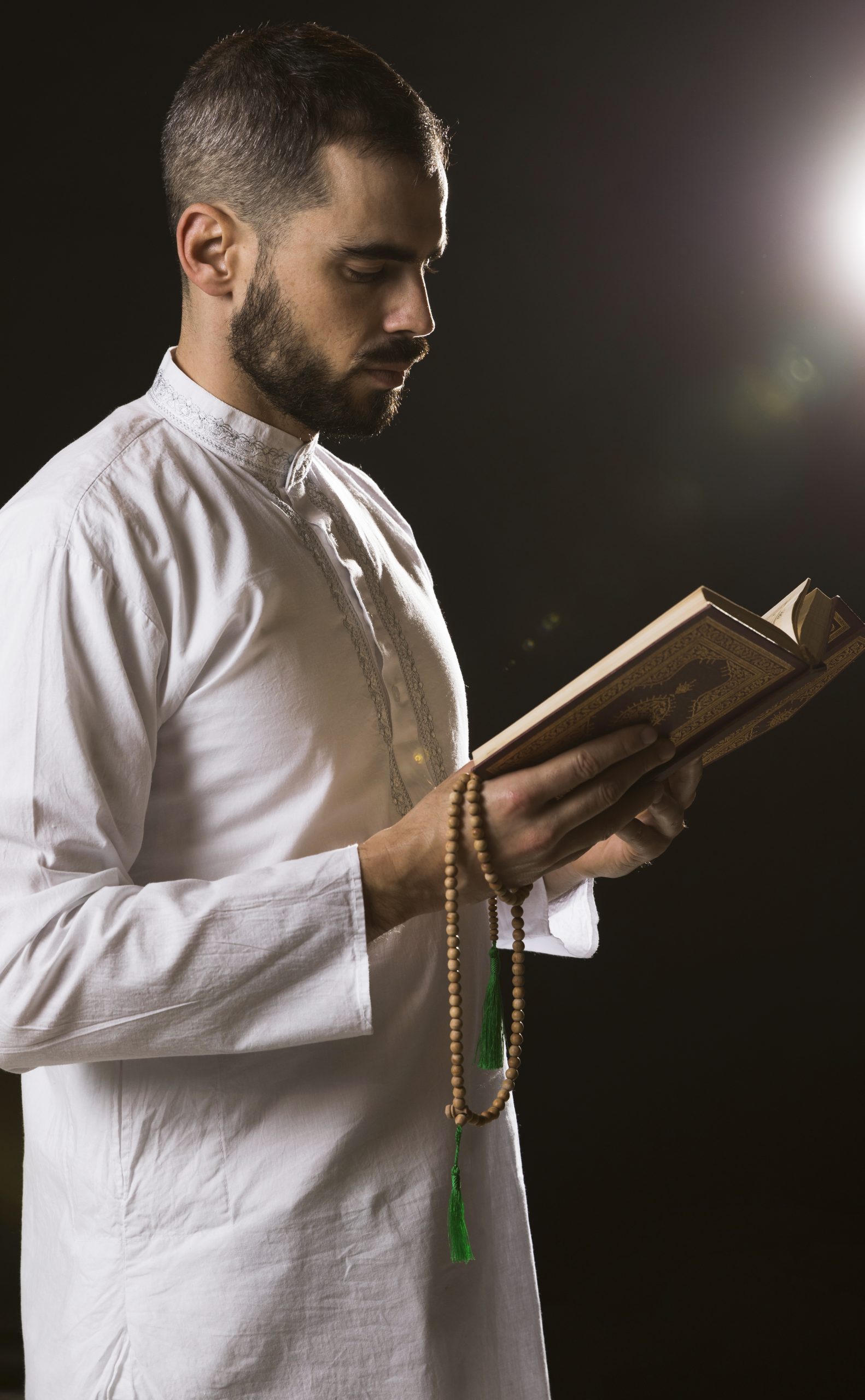 Muslim man revising Quran with prayer beads during Hifz practice.
